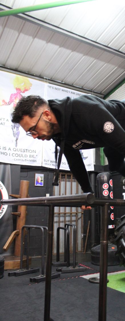 A calisthenics gym member doing a weighted pullup