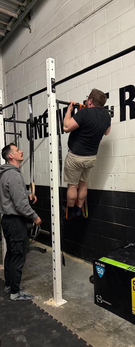 A calisthenics gym member doing a weighted pullup