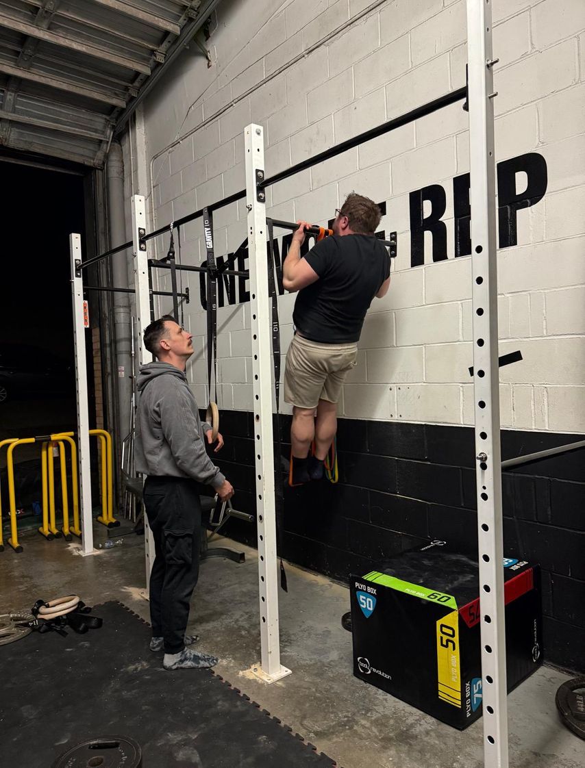 A calisthenics  gym member doing a weighted pullup
