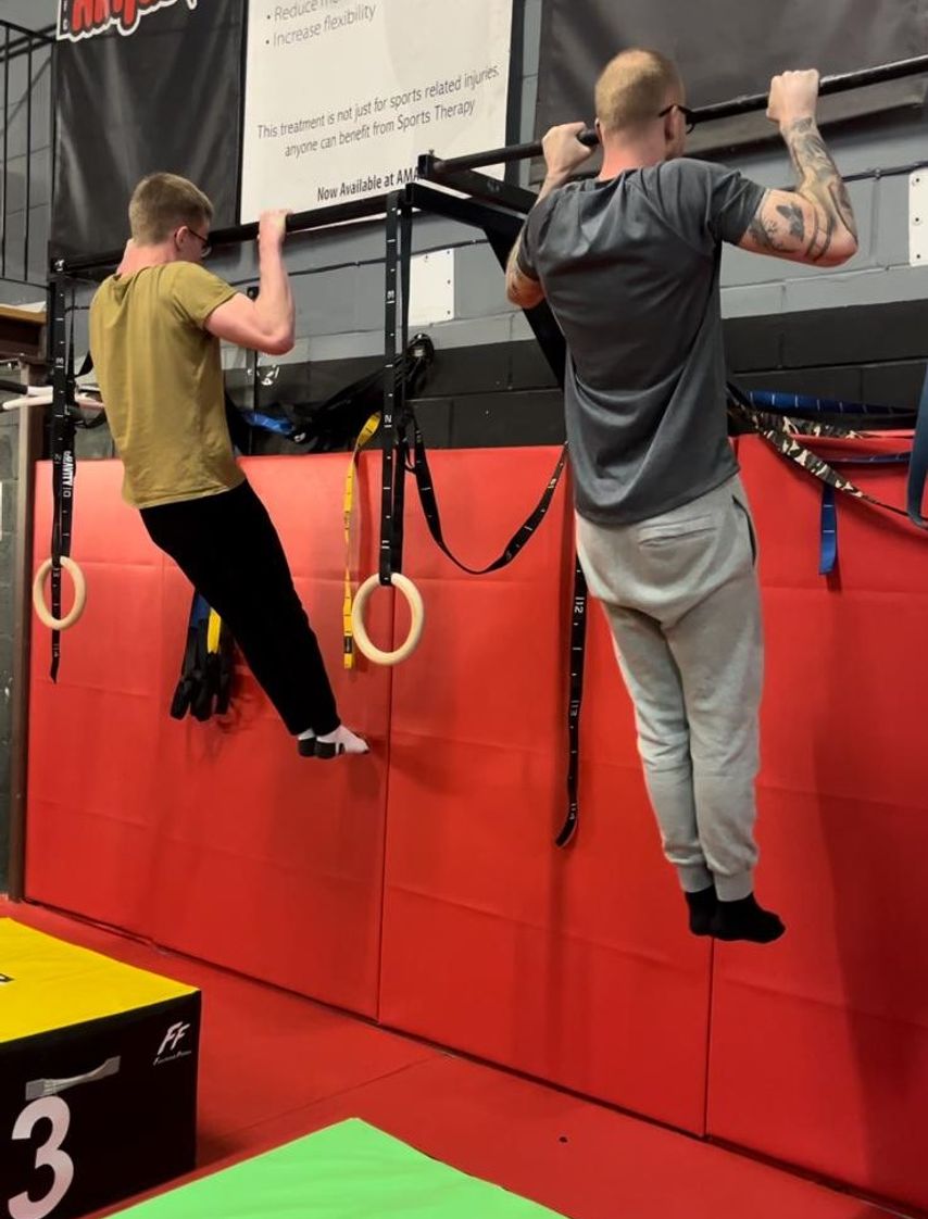 Two Cali Fit athletes competing in a pullup-hold challenge