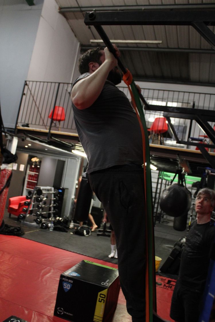 A calisthenics gym member doing a pull up