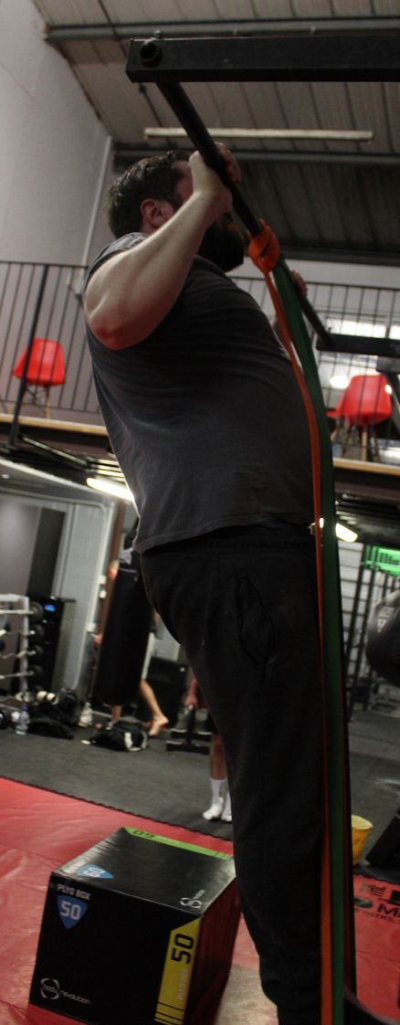 A calisthenics gym member doing a pull up